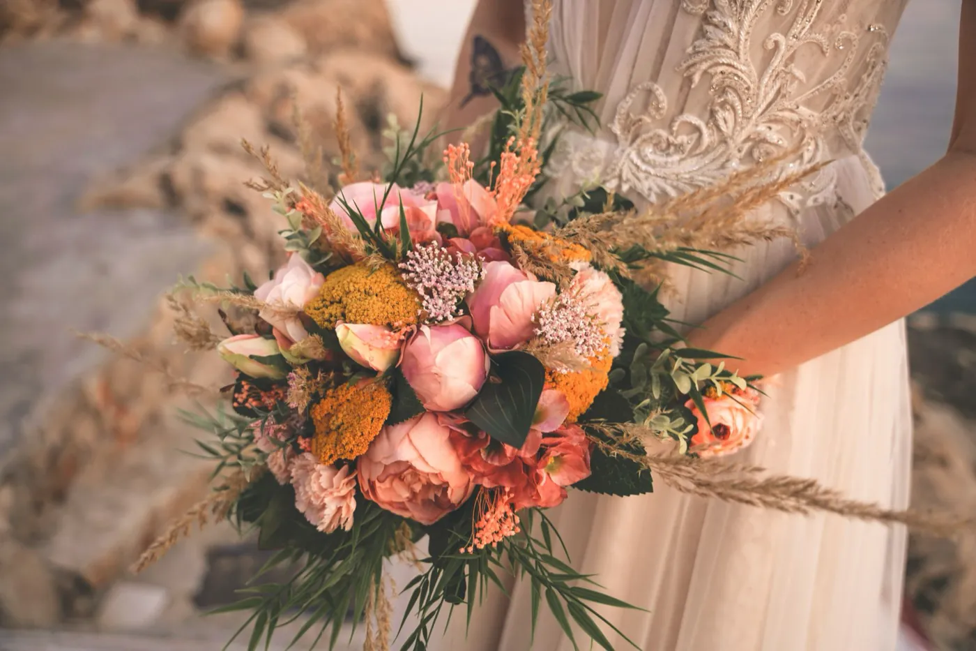 A close-up bridal bouquet of terracotta and peach roses with wildflowers.